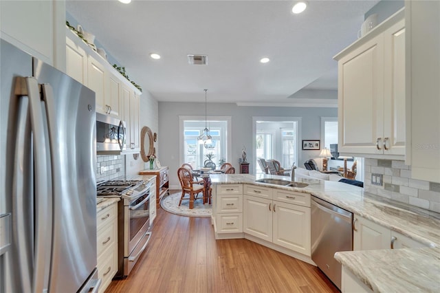 kitchen featuring stainless steel appliances, sink, light hardwood / wood-style floors, and backsplash