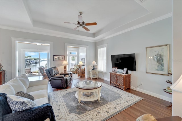 living room with ceiling fan, ornamental molding, a tray ceiling, and hardwood / wood-style floors