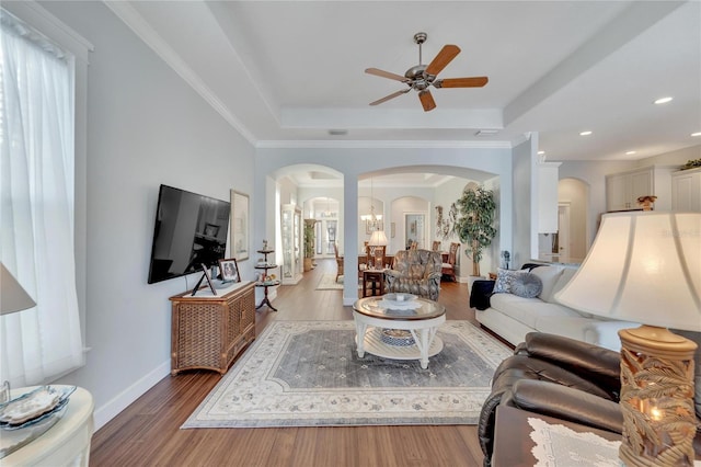 living room with crown molding, wood-type flooring, ceiling fan, and a raised ceiling