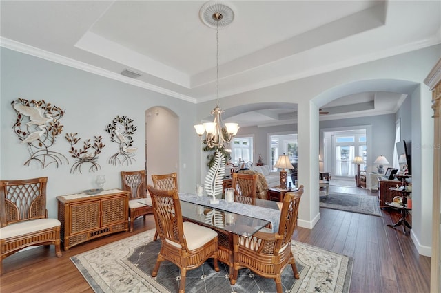 dining room featuring a tray ceiling, wood-type flooring, crown molding, and an inviting chandelier