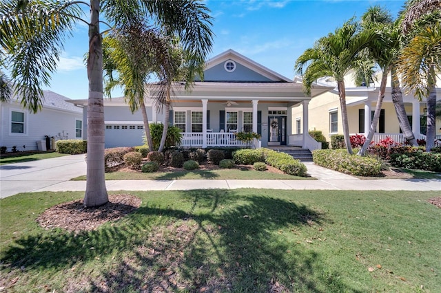 view of front of home with covered porch, a garage, and a front lawn