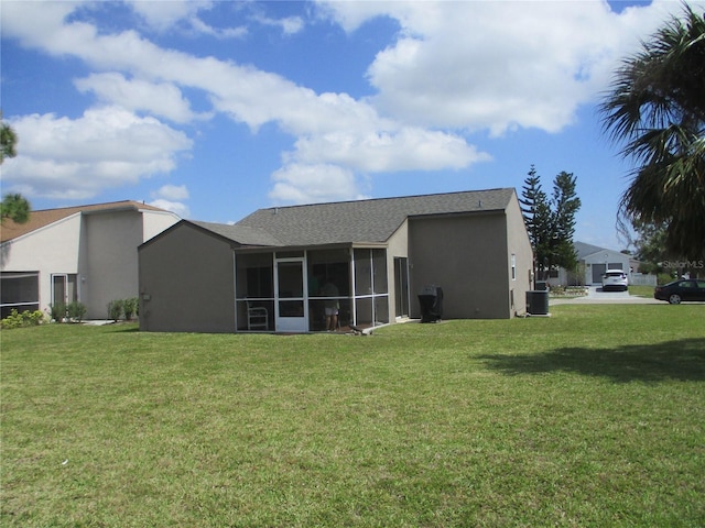 back of house featuring a sunroom, central AC unit, and a lawn