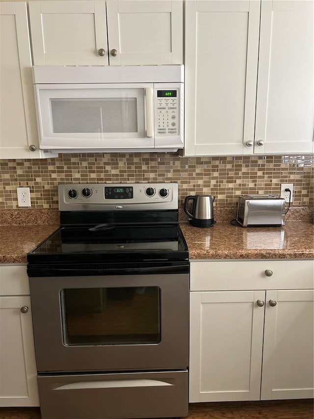 kitchen featuring stainless steel electric stove, tasteful backsplash, white cabinets, and dark stone counters