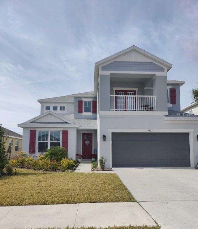 view of front facade with a balcony, a front lawn, and a garage