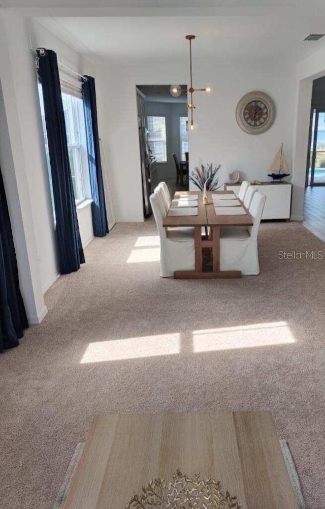 unfurnished dining area with light colored carpet and a chandelier