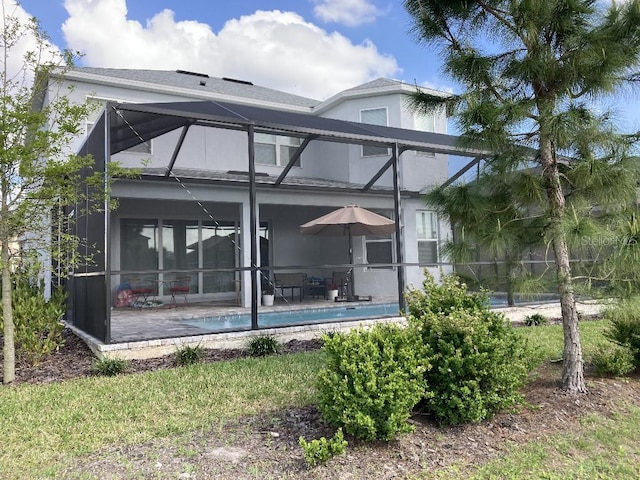 rear view of property featuring glass enclosure and a patio area