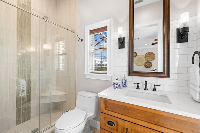 bathroom with ceiling fan, vanity, a shower with shower door, and toilet