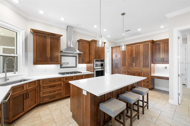 kitchen featuring backsplash, wall chimney range hood, sink, a breakfast bar area, and stainless steel appliances