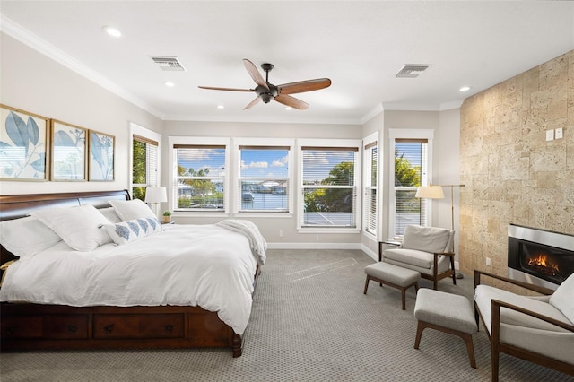 carpeted bedroom with ceiling fan, a fireplace, and crown molding