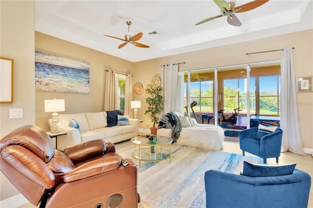 living room with a tray ceiling and ceiling fan