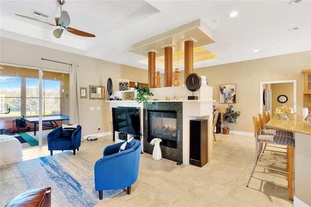 tiled living room with a tray ceiling and ceiling fan