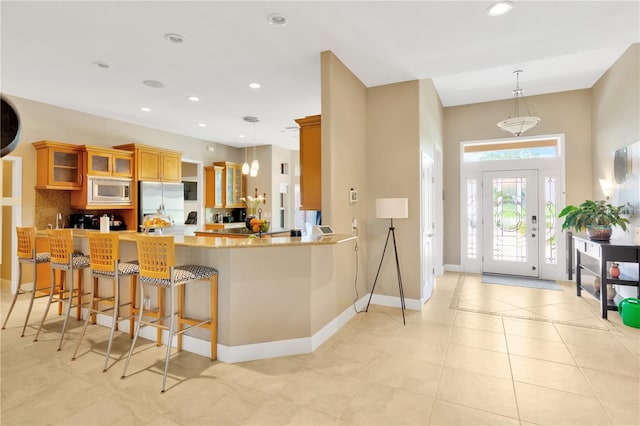 kitchen with pendant lighting, kitchen peninsula, appliances with stainless steel finishes, and light tile floors