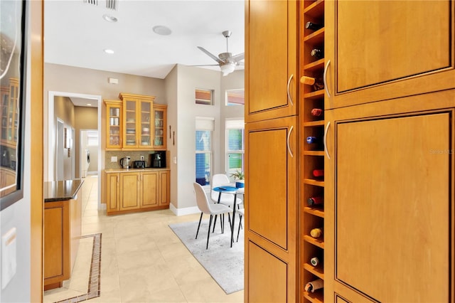 kitchen with ceiling fan, light tile floors, and dark stone counters