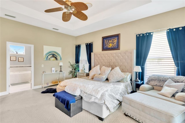 carpeted bedroom with a raised ceiling, ceiling fan, and ensuite bathroom