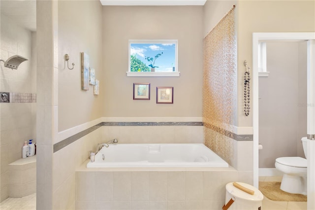 bathroom featuring tiled tub, toilet, and tile flooring