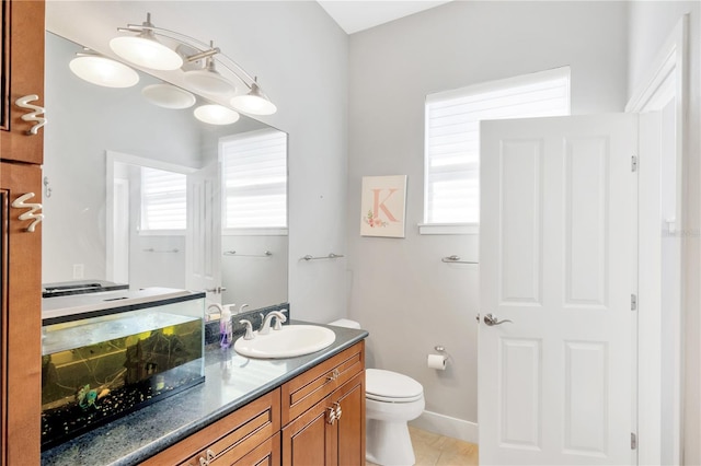 bathroom with plenty of natural light, tile flooring, toilet, and vanity