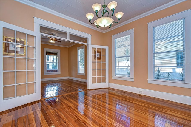 empty room featuring ceiling fan with notable chandelier, hardwood / wood-style flooring, and crown molding