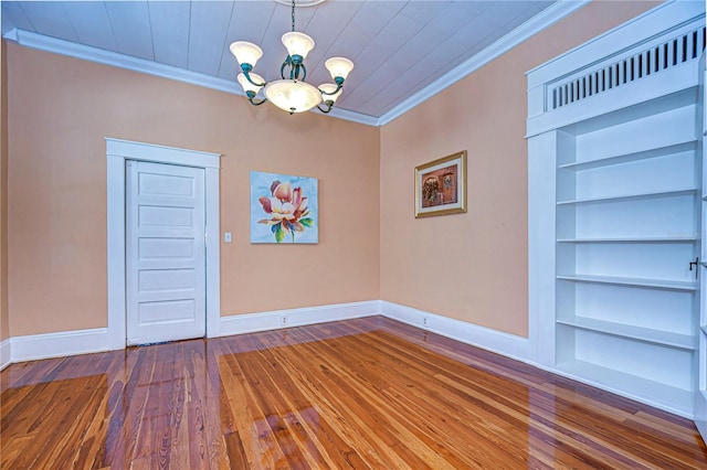 unfurnished dining area with hardwood / wood-style flooring, crown molding, a notable chandelier, and built in features