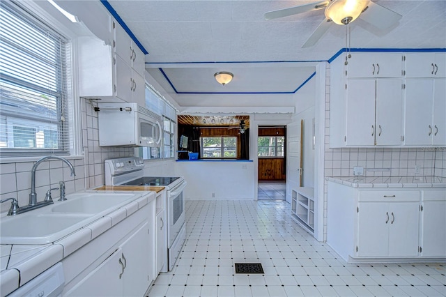 kitchen with sink, white cabinetry, backsplash, white appliances, and tile countertops