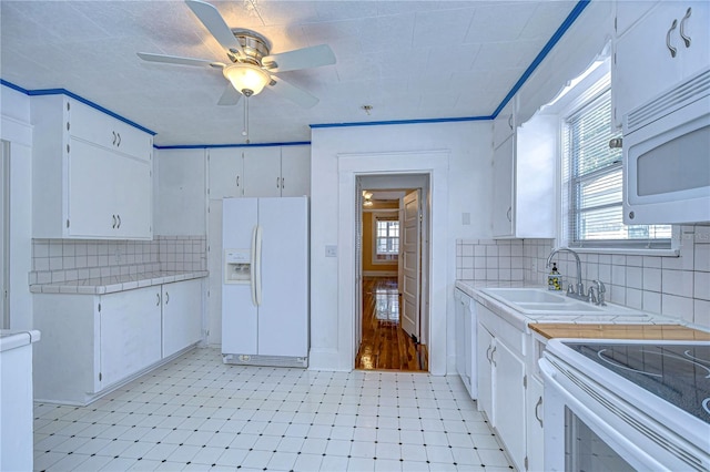 kitchen with white appliances, tile countertops, white cabinetry, and sink