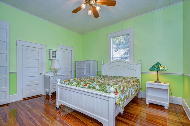 bedroom with ornamental molding, ceiling fan, and dark wood-type flooring