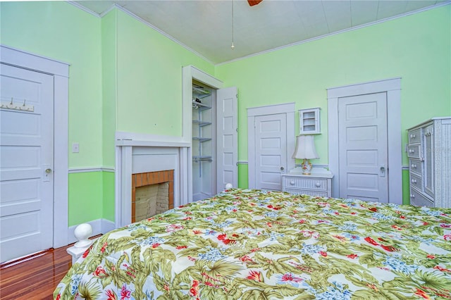 bedroom with ceiling fan, two closets, dark hardwood / wood-style floors, and ornamental molding