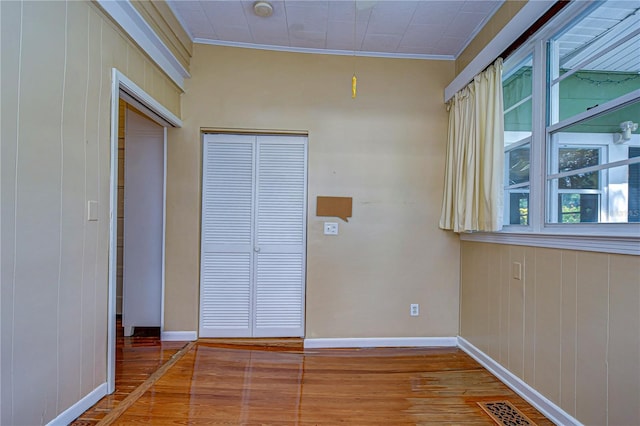 interior space featuring crown molding, wood walls, and hardwood / wood-style floors