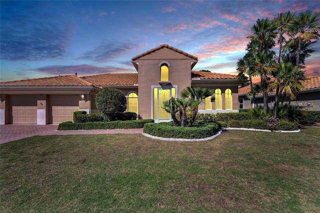 mediterranean / spanish-style home with a yard and a garage