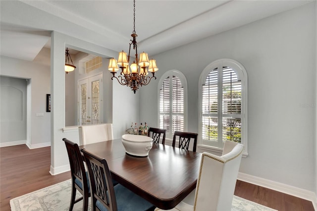 dining room with a notable chandelier, plenty of natural light, and dark hardwood / wood-style flooring