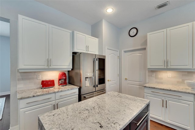 kitchen featuring backsplash, high quality fridge, white cabinets, and light hardwood / wood-style flooring