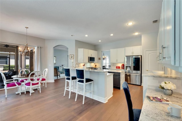 kitchen with stainless steel appliances, light hardwood / wood-style flooring, white cabinetry, and a wealth of natural light