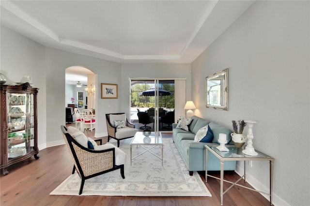 living room featuring a tray ceiling, hardwood / wood-style floors, and an inviting chandelier