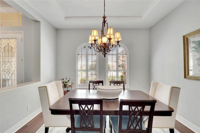 dining room featuring an inviting chandelier, wood-type flooring, and a tray ceiling