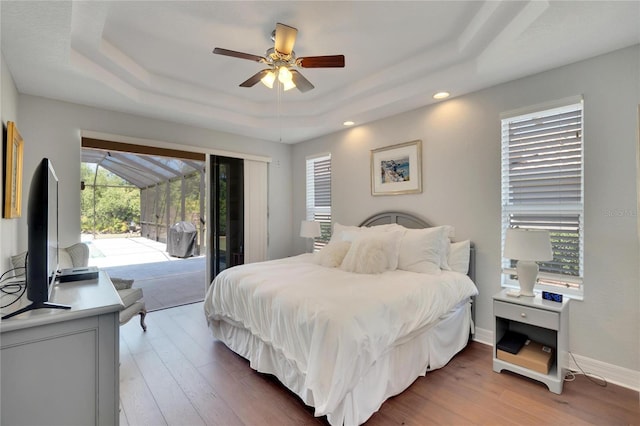 bedroom featuring a raised ceiling, hardwood / wood-style floors, and access to outside