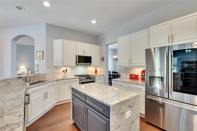 kitchen featuring sink, white cabinets, appliances with stainless steel finishes, backsplash, and light stone countertops