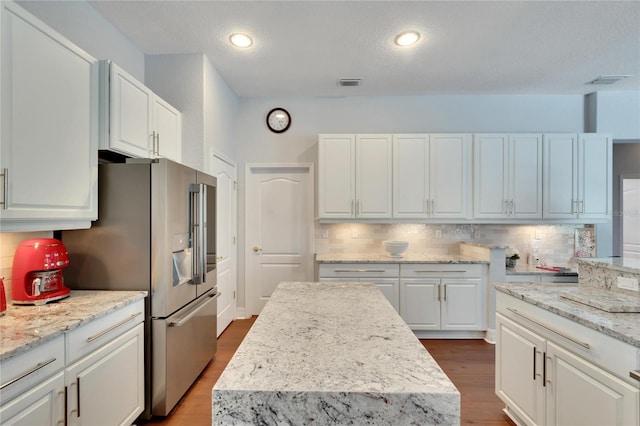 kitchen featuring light stone countertops, hardwood / wood-style floors, a center island, and white cabinetry