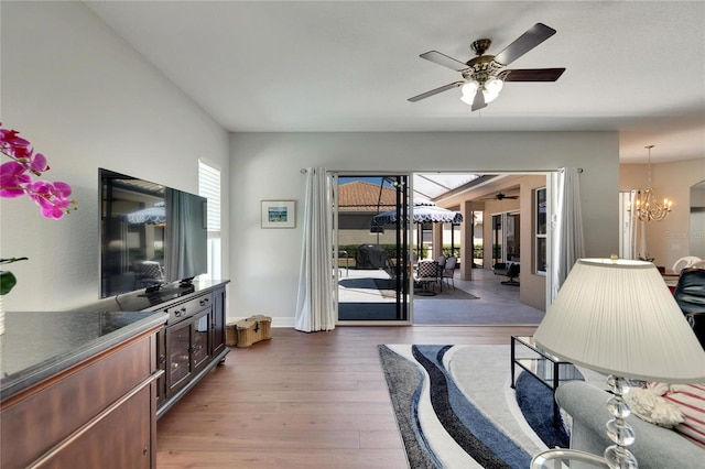 living room with light hardwood / wood-style floors, french doors, and ceiling fan with notable chandelier