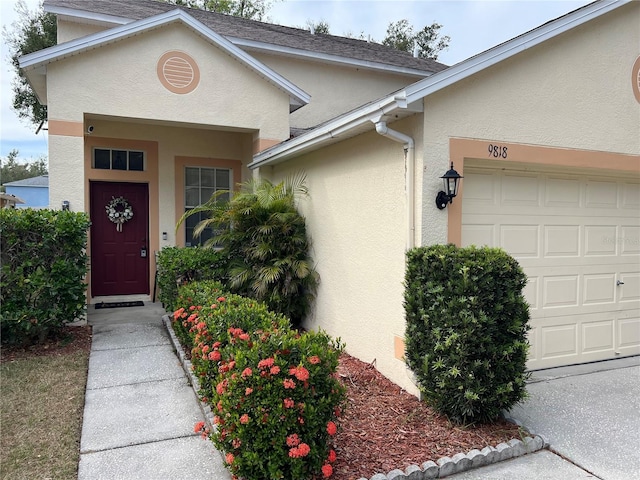 entrance to property featuring a garage and stucco siding