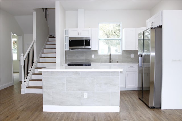 kitchen with a kitchen island, light wood-type flooring, white cabinetry, and appliances with stainless steel finishes