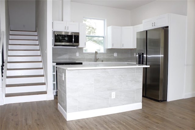 kitchen featuring backsplash, a center island, white cabinetry, and appliances with stainless steel finishes