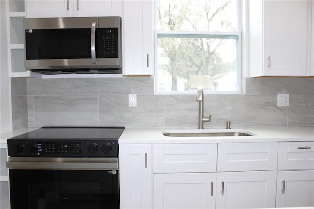 kitchen featuring sink, backsplash, white cabinetry, and electric range oven