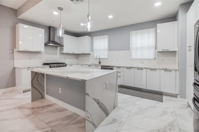 kitchen featuring a center island, decorative light fixtures, wall chimney exhaust hood, white cabinets, and range