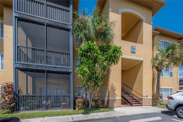 view of building exterior with uncovered parking and stairway