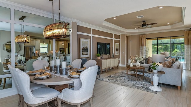 dining area featuring a raised ceiling, ornamental molding, and ceiling fan with notable chandelier