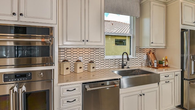 kitchen featuring cream cabinets, backsplash, sink, and stainless steel appliances