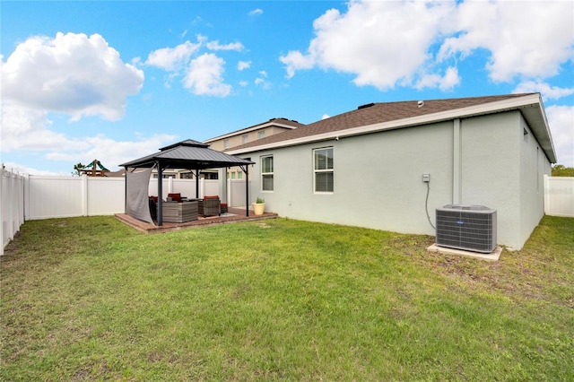 back of house with a yard, stucco siding, a gazebo, central AC unit, and a fenced backyard