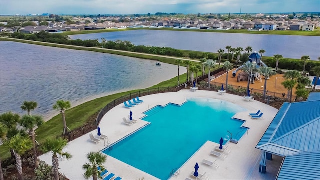 community pool with a water view, fence, and a residential view