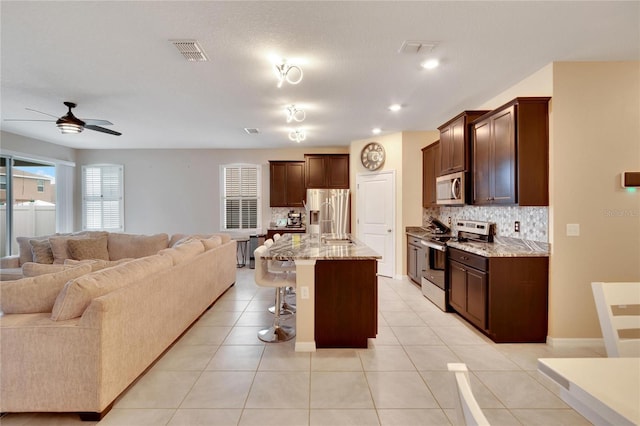 kitchen featuring stainless steel appliances, visible vents, decorative backsplash, open floor plan, and light tile patterned flooring