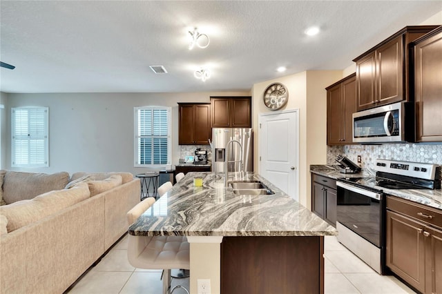 kitchen with open floor plan, appliances with stainless steel finishes, a breakfast bar area, and light tile patterned flooring