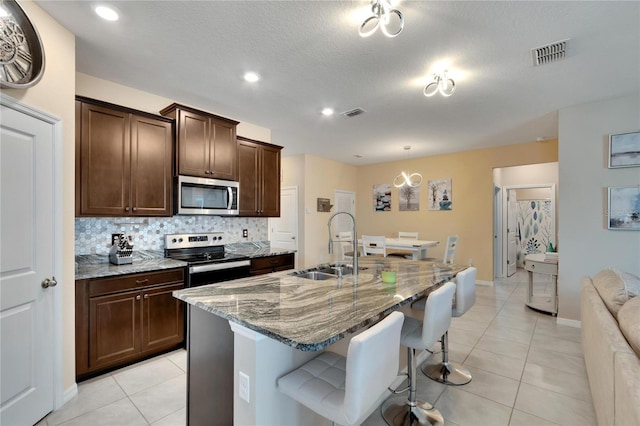 kitchen with light tile patterned floors, visible vents, decorative backsplash, stainless steel appliances, and a sink